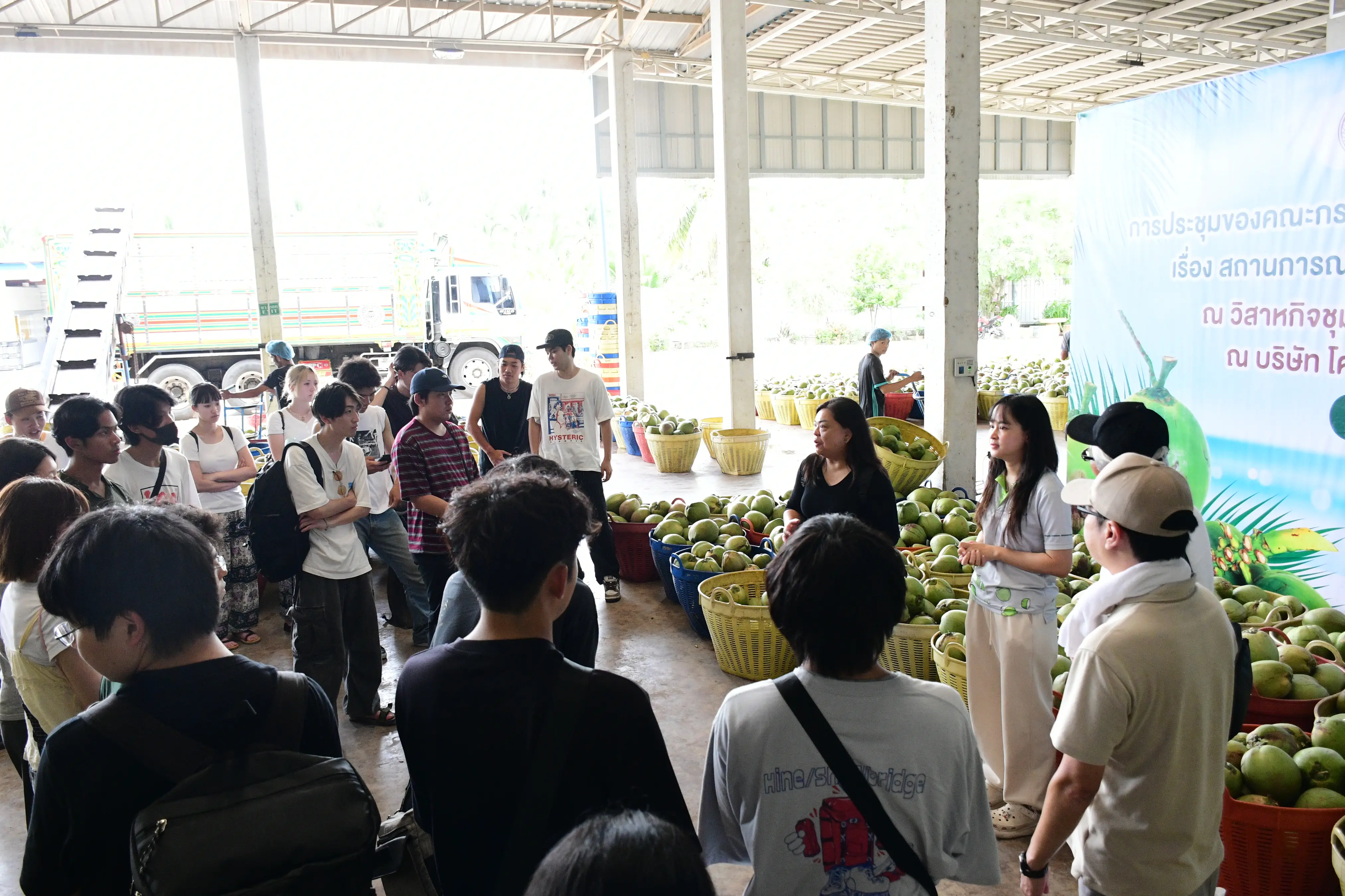 Faculty and students listening to a briefing at the area where aromatic coconuts are received and selected from the orchards